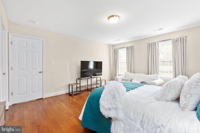 bedroom with multiple windows and hardwood / wood-style floors