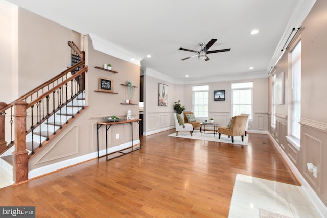 living area with crown molding, ceiling fan, and light hardwood / wood-style floors