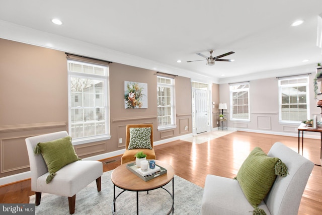 living room featuring ceiling fan, ornamental molding, and light wood-type flooring