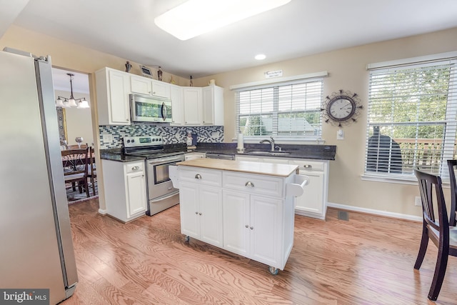 kitchen featuring appliances with stainless steel finishes, a kitchen island, and white cabinets