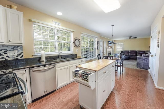 kitchen featuring sink, light hardwood / wood-style flooring, stainless steel appliances, white cabinets, and decorative light fixtures