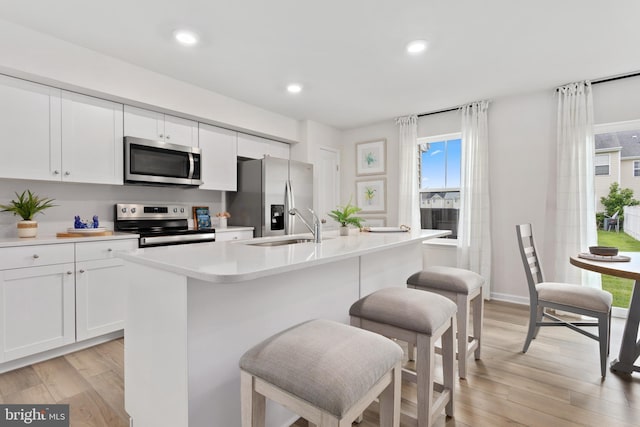 kitchen featuring a kitchen island with sink, sink, a wealth of natural light, appliances with stainless steel finishes, and white cabinetry