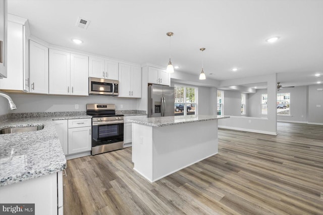 kitchen with sink, decorative light fixtures, white cabinets, and appliances with stainless steel finishes