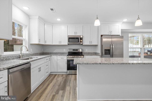 kitchen with appliances with stainless steel finishes, decorative light fixtures, sink, and white cabinets