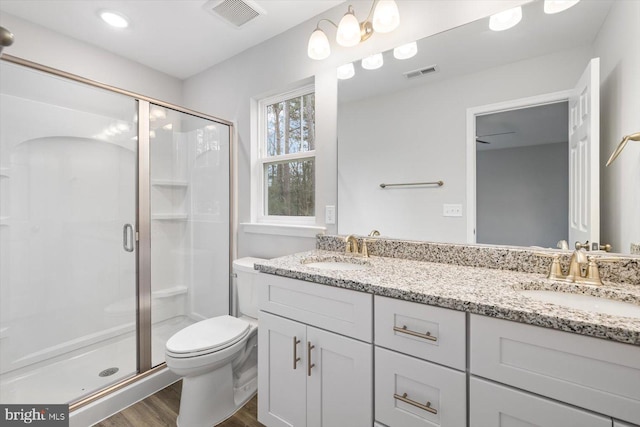 bathroom with hardwood / wood-style flooring, vanity, an enclosed shower, and toilet