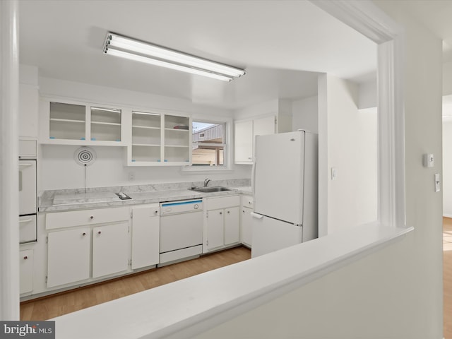 kitchen with sink, white appliances, light hardwood / wood-style floors, and white cabinets