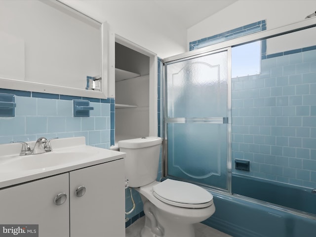 full bathroom with toilet, combined bath / shower with glass door, tile walls, vanity, and decorative backsplash