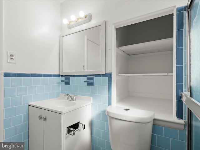 bathroom featuring vanity, toilet, and tile walls