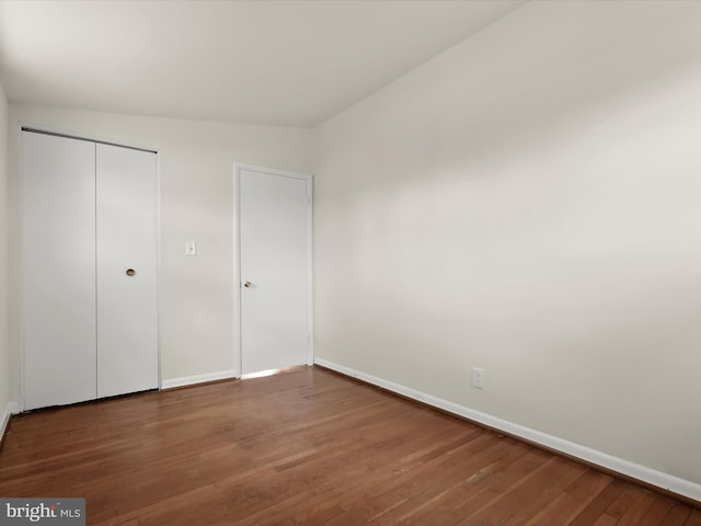 unfurnished bedroom with dark hardwood / wood-style floors and a closet