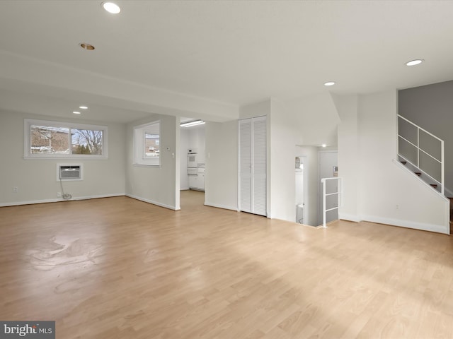 unfurnished living room featuring heating unit, light hardwood / wood-style floors, and a wall unit AC