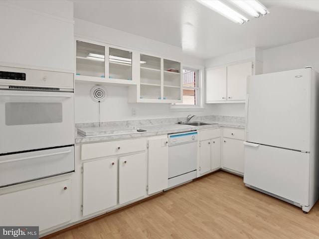 kitchen with white cabinetry, sink, white appliances, and light hardwood / wood-style floors