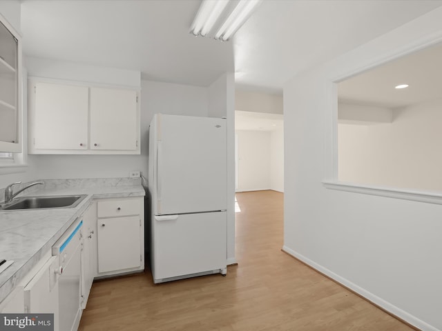 kitchen with white cabinetry, sink, white appliances, and light hardwood / wood-style floors