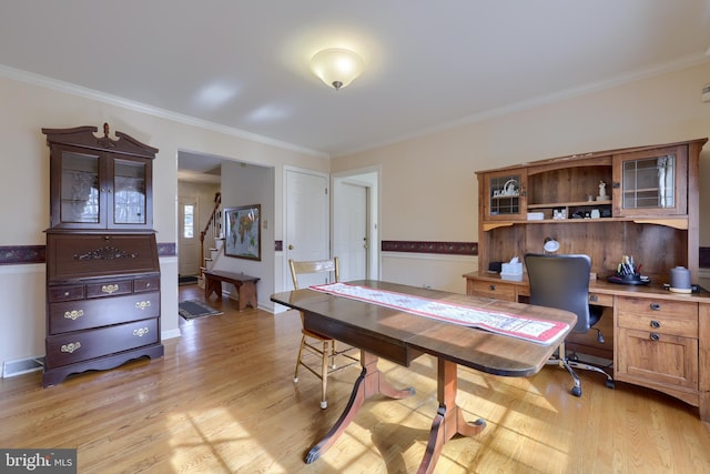 home office featuring light wood-style floors, wainscoting, visible vents, and crown molding