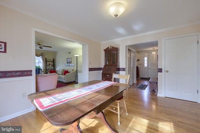 dining room featuring ornamental molding, wainscoting, and light wood finished floors