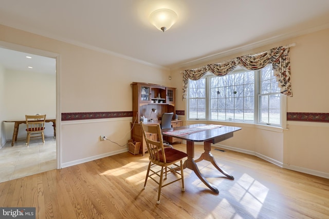 dining room featuring a wainscoted wall, crown molding, baseboards, and wood finished floors