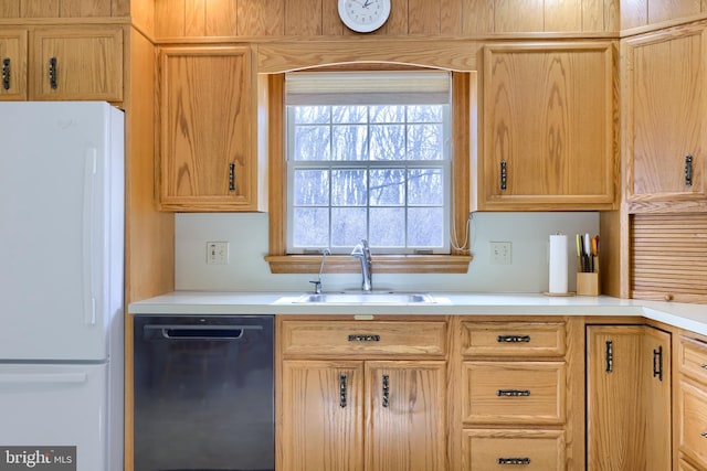 kitchen featuring a sink, light countertops, dishwasher, and freestanding refrigerator