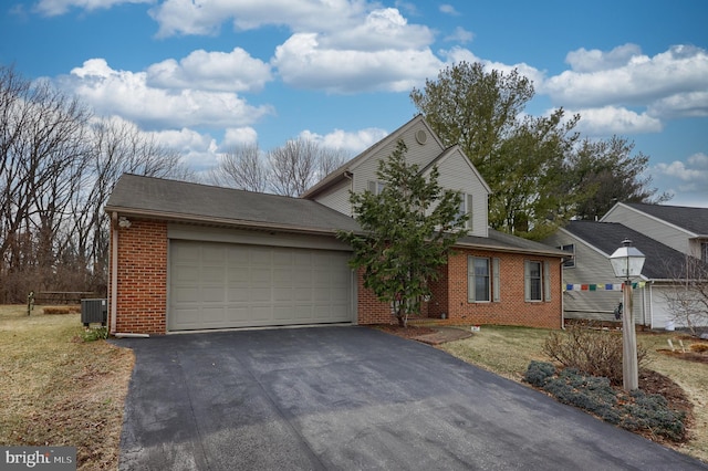 traditional-style home featuring aphalt driveway, brick siding, and a garage