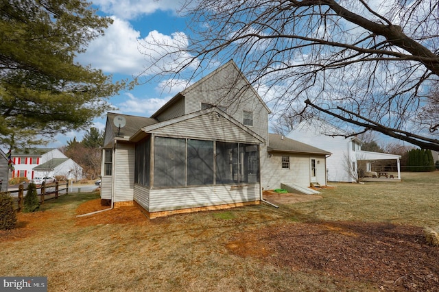 back of property with a sunroom, fence, and a lawn