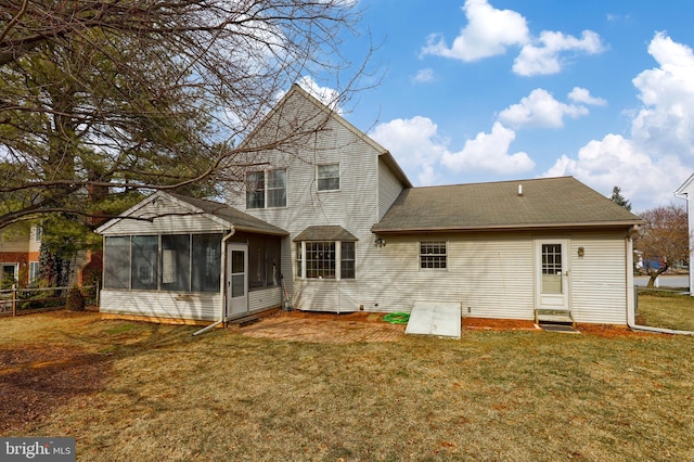 back of house with entry steps, a yard, fence, and a sunroom