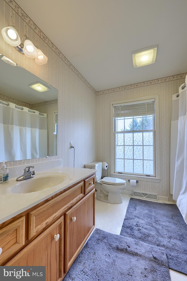 full bathroom with toilet, visible vents, vanity, and wallpapered walls