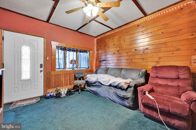 carpeted living room featuring ceiling fan, wood walls, a textured ceiling, and lofted ceiling with beams