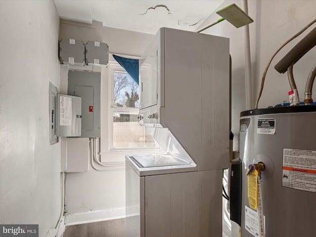 laundry room with stacked washer / dryer, electric panel, and water heater