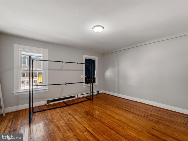 spare room featuring wood-type flooring and a baseboard heating unit