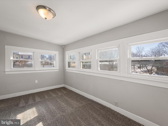 spare room featuring dark carpet