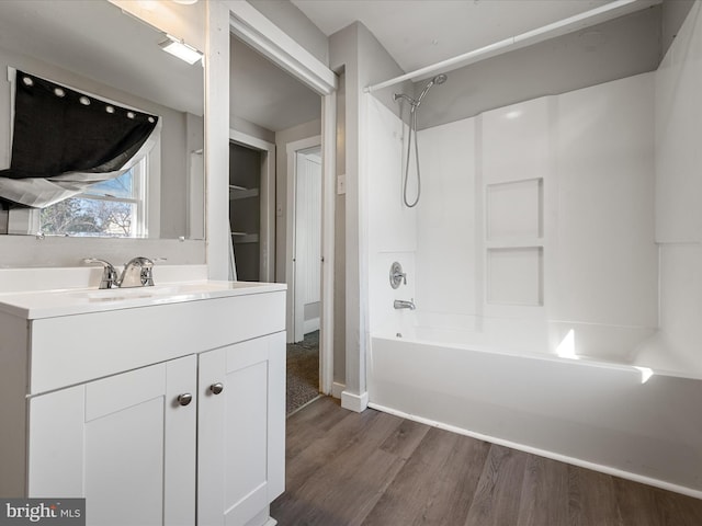 bathroom with hardwood / wood-style floors,  shower combination, and vanity