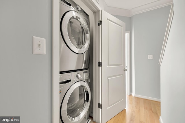 laundry room with ornamental molding, light hardwood / wood-style floors, and stacked washer / dryer