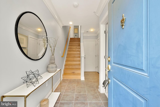 foyer entrance with crown molding and light tile patterned floors