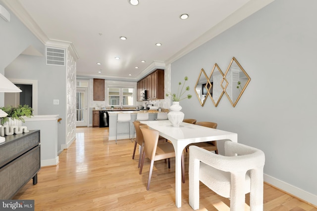 dining area featuring light wood-type flooring and crown molding