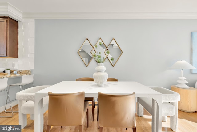 dining space featuring ornamental molding and light hardwood / wood-style flooring