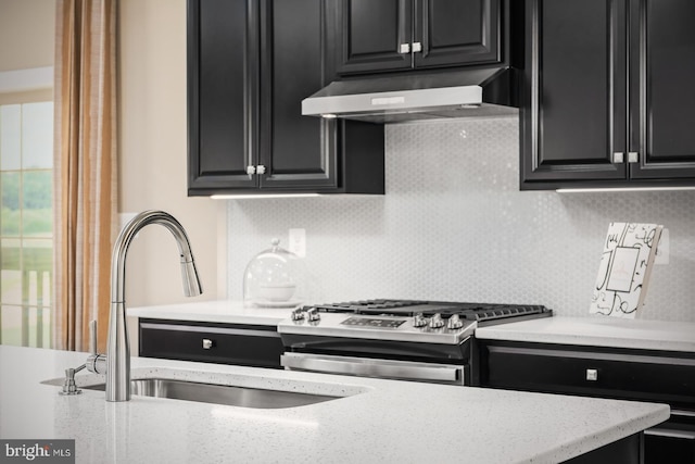 kitchen featuring stainless steel range with gas cooktop, sink, backsplash, and light stone counters