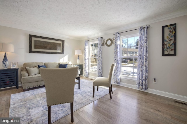 living room with a textured ceiling, ornamental molding, a wealth of natural light, and hardwood / wood-style floors