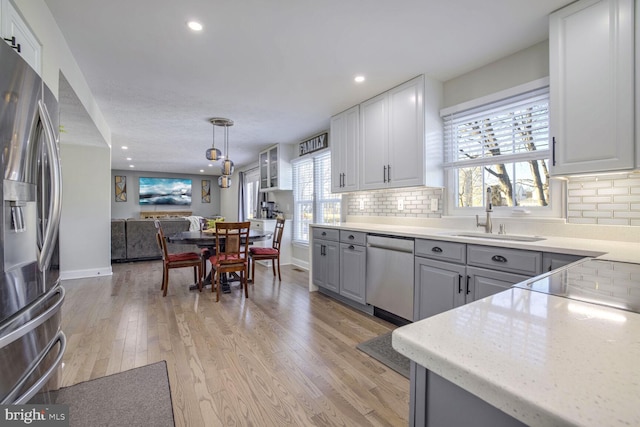 kitchen featuring sink, backsplash, hanging light fixtures, gray cabinetry, and appliances with stainless steel finishes