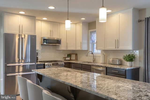 kitchen featuring sink, stainless steel appliances, white cabinetry, and hanging light fixtures