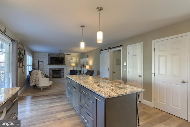 kitchen featuring a kitchen island, light stone counters, hanging light fixtures, and a barn door