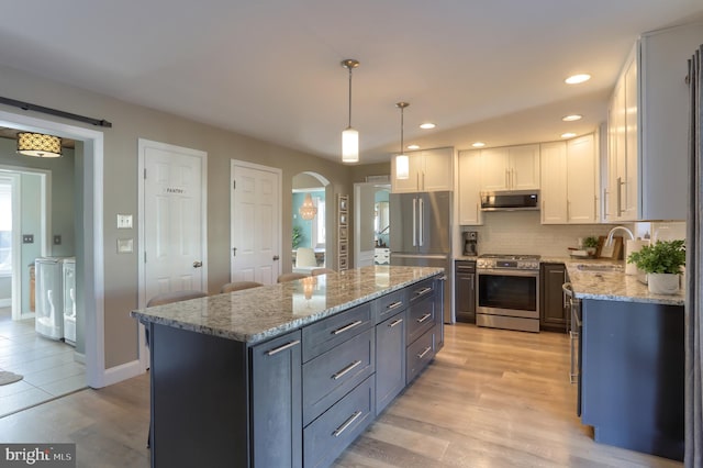 kitchen featuring a center island, white cabinets, washer and dryer, appliances with stainless steel finishes, and sink