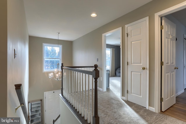 corridor with carpet flooring and a notable chandelier