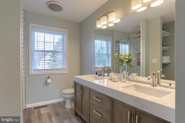 bathroom with a tile shower, vanity, toilet, and hardwood / wood-style floors