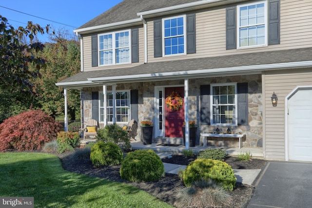 view of front of home featuring a front yard, a garage, and a porch