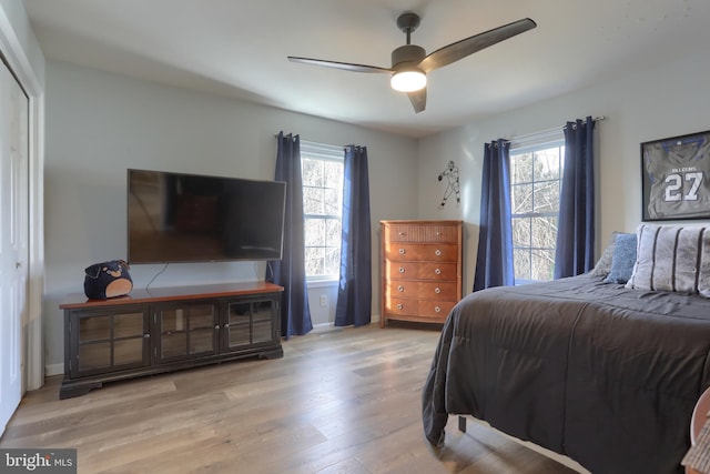 bedroom with ceiling fan, light hardwood / wood-style flooring, a closet, and multiple windows