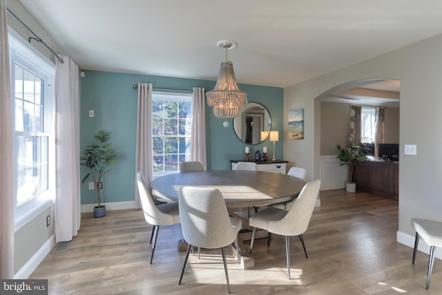 dining space with hardwood / wood-style floors and a notable chandelier