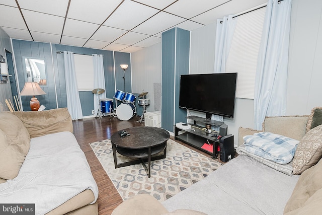 living room with a drop ceiling and wood-type flooring