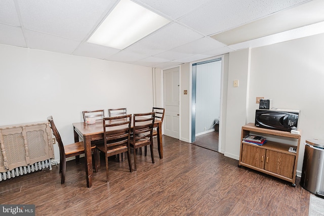 dining room with dark hardwood / wood-style flooring and a drop ceiling