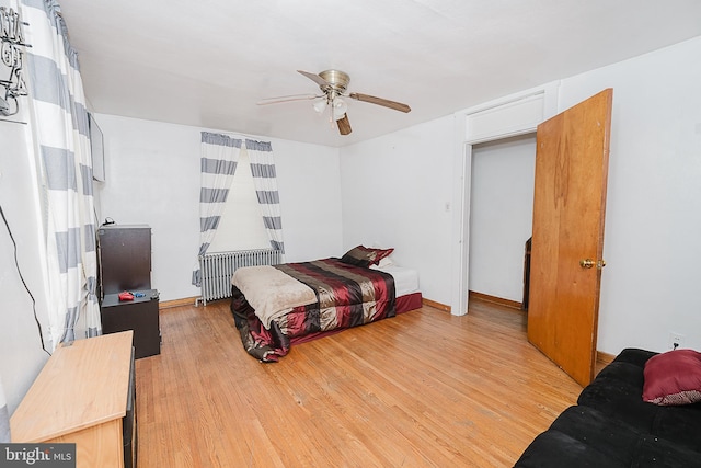 bedroom with ceiling fan, radiator heating unit, and light wood-type flooring