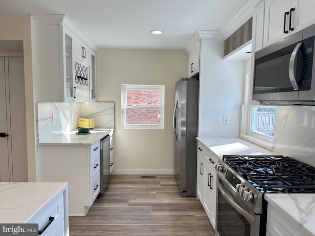 kitchen featuring light stone countertops, white cabinetry, stainless steel appliances, and tasteful backsplash