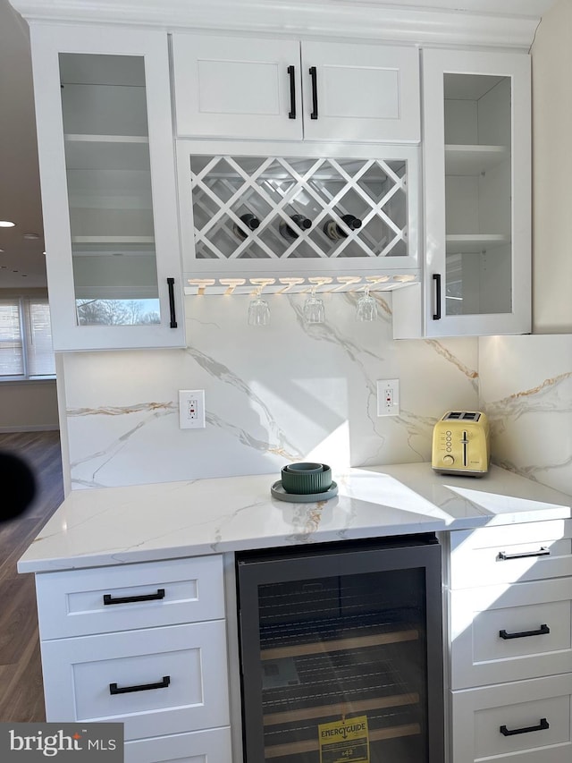 bar featuring white cabinets, beverage cooler, backsplash, and light stone counters