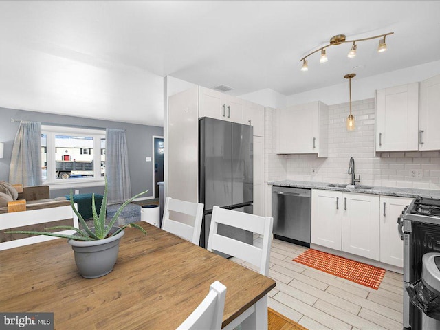 kitchen with decorative light fixtures, backsplash, stainless steel appliances, and white cabinetry